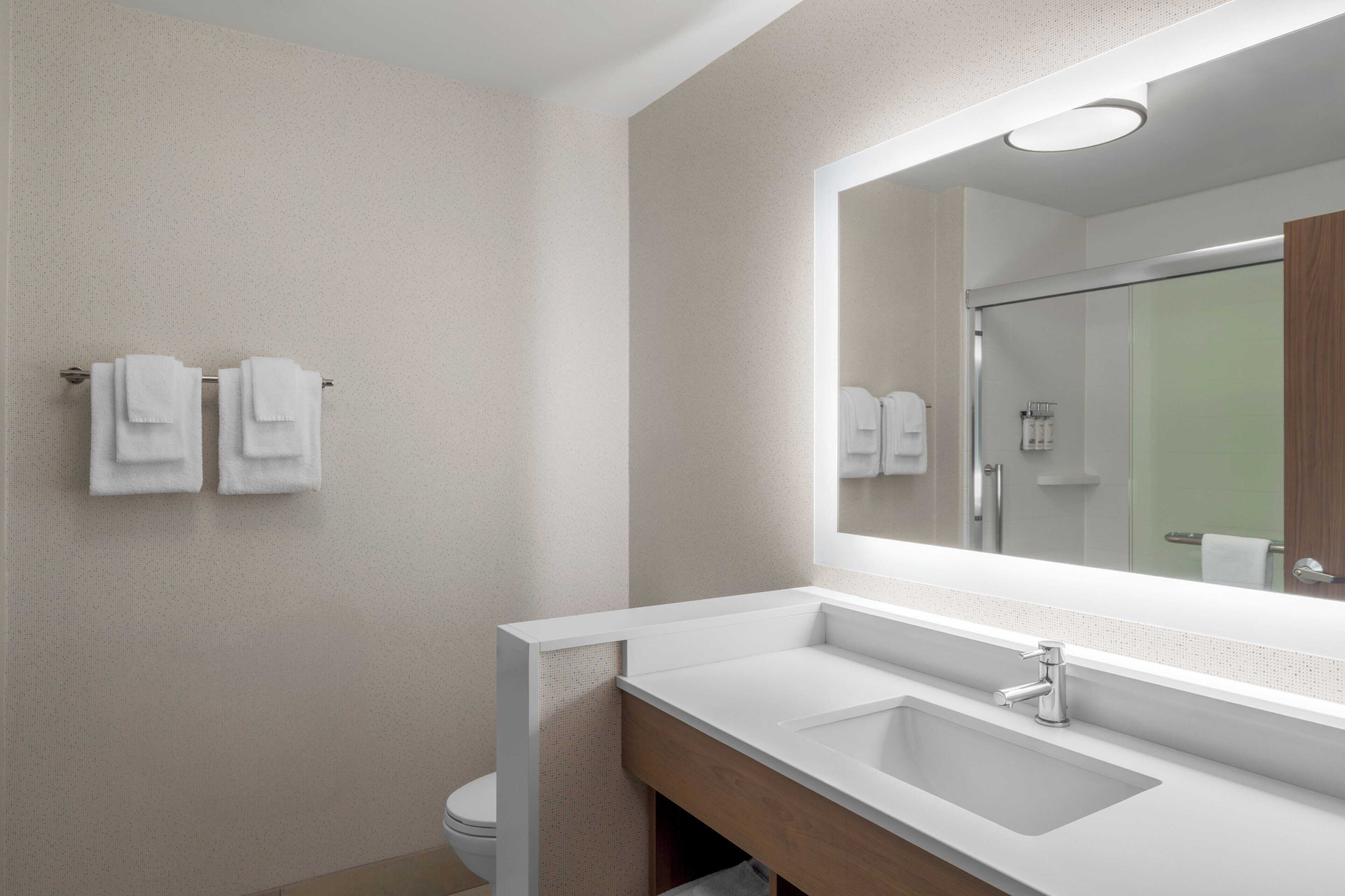 A modern bathroom with a white sink, a mirror, and two towels on a towel rack.