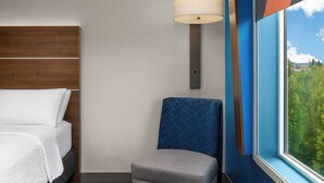 A hotel room with a bed, a chair, a window, and a wall-mounted lamp. - Holiday Inn Express & Suites Salem North - Keizer by IHG (Keizer)
