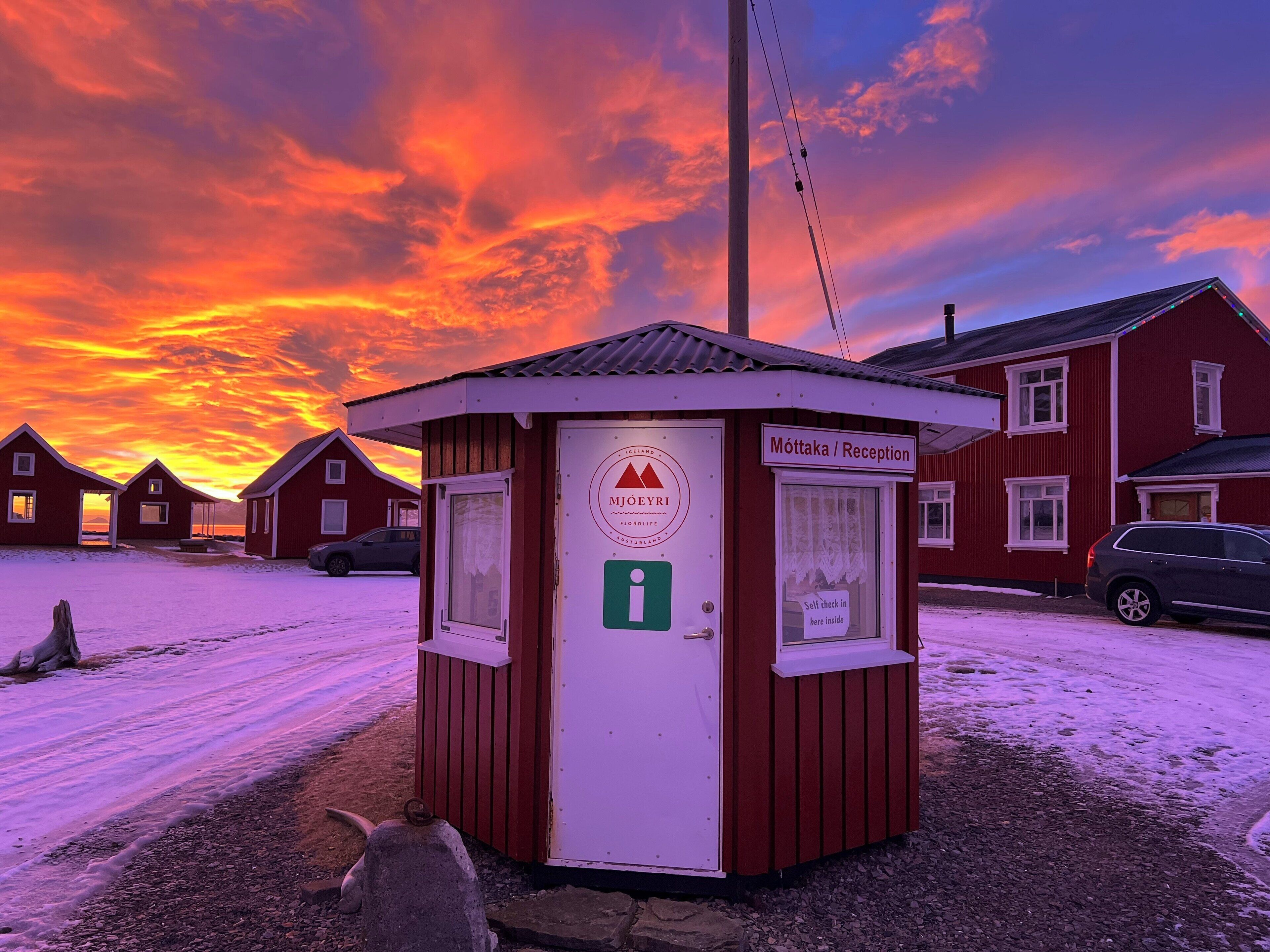Un petit bâtiment d’accueil avec une enseigne indiquant « Möttaka / Réception » et un logo pour « Mjöneyri Fjordlife Austurland ».