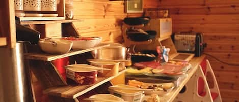 Cocina de cabaña de madera con estantes llenos de frascos, cuencos y recipientes.