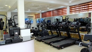 Une salle de sport équipée de tapis de course, de vélos elliptiques et d’appareils de musculation.