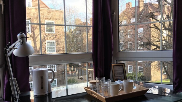 A room with a large window, a table with a tray of cups and a kettle, and a lamp. - Beechwood House (London)