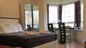 A bedroom with a bed, a desk, a chair, and a window with curtains. - Beechwood House (London)