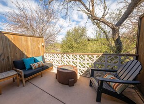 An outdoor patio with a wooden deck, a sofa with cushions, a round table, and a chair.