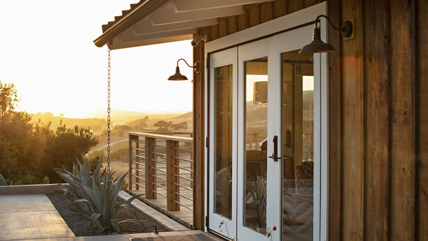 Ein Holzhaus mit Glastür und einem Balkon mit Blick auf eine Landschaft.