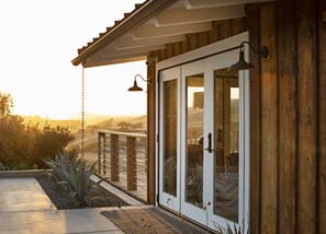 A wooden house with a glass door and a balcony overlooking a landscape.