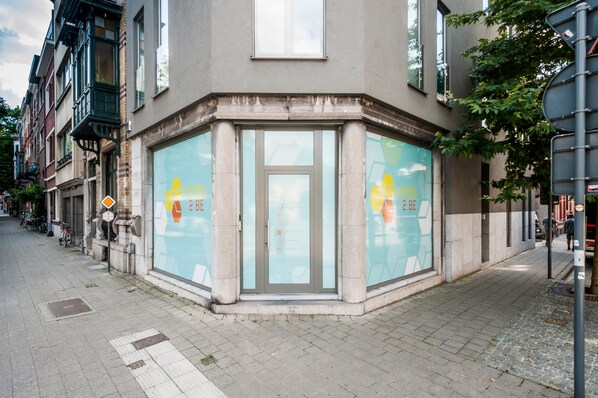 A corner building with a large glass door and a sign with "2 BE" on it. - Ooostel2.be Leuven (Leuven)