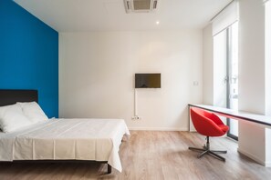 A modern bedroom with a bed, a TV mounted on the wall, and a red chair. - Ooostel2.be Leuven (Leuven)