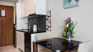 A modern kitchen with a built-in oven, a coffee maker, and a dining area with a table and chairs. - Water Park Condominium by Able Estate (Pattaya)