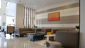 A modern hotel lobby with a seating area, a large painting on the wall, and a polished floor. - Rivertel (Teluk Intan)