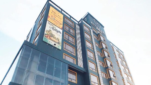 A multi-story hotel with a prominent entrance, large windows, and a sign advertising a local restaurant. - Rivertel (Teluk Intan)
