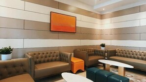 A modern lounge area with leather sofas, a white coffee table, and a small orange ottoman. - Rivertel (Teluk Intan)