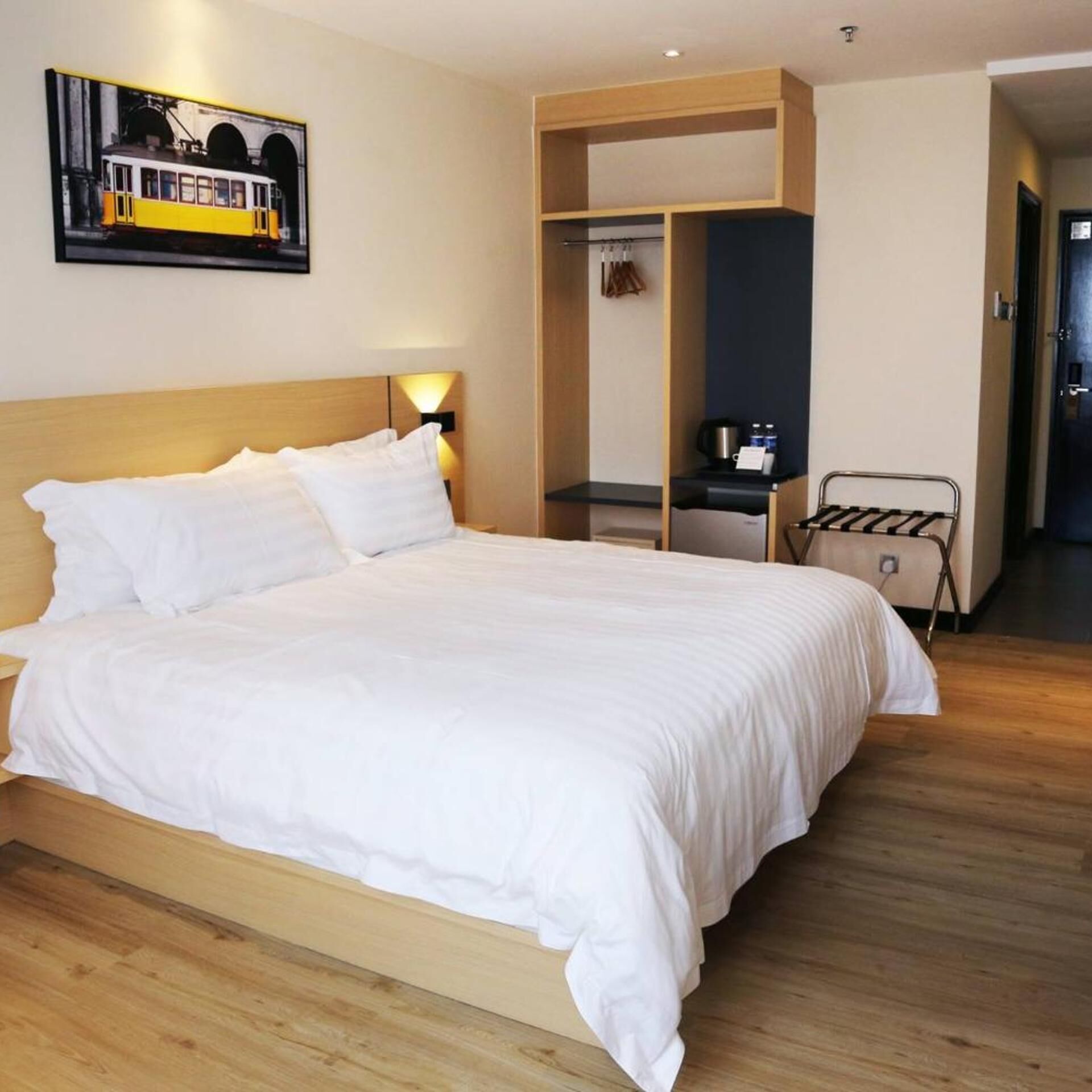Una habitación de hotel con una cama grande, un armario, un escritorio con una silla y un perchero.