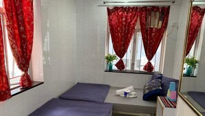 A hotel room with two beds, a small table, a mirror, and red curtains. - New Yan Yan Guest House (Kowloon)