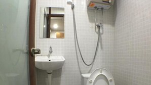 A small, tiled bathroom with a toilet, sink, and shower. - New Yan Yan Guest House (Kowloon)
