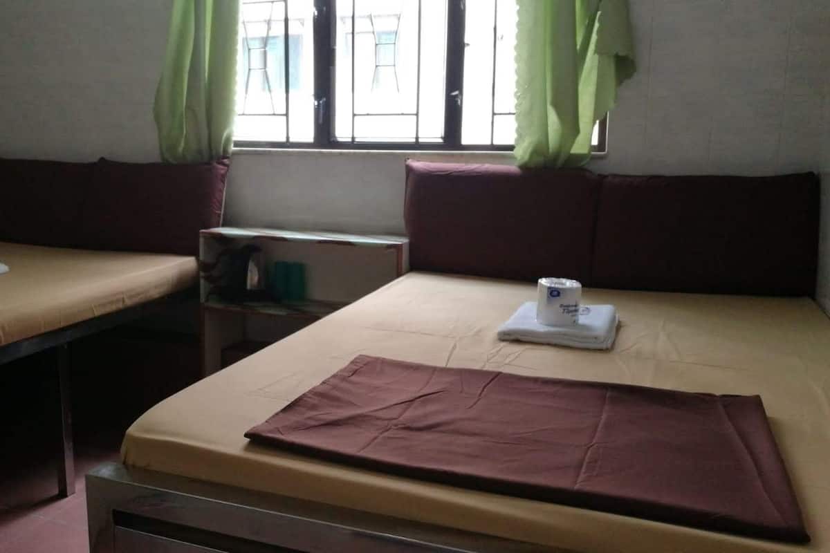 A room with two single beds, a small table, and a window with curtains.