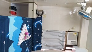 A small bathroom with a shower curtain depicting a night sky, a white sink, a kettle, and a fan. - New Yan Yan Guest House (Kowloon)