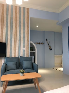 A living room with a sofa, a coffee table, a TV mounted on the wall, and a decorative wall panel. - Canova (Ji'an)