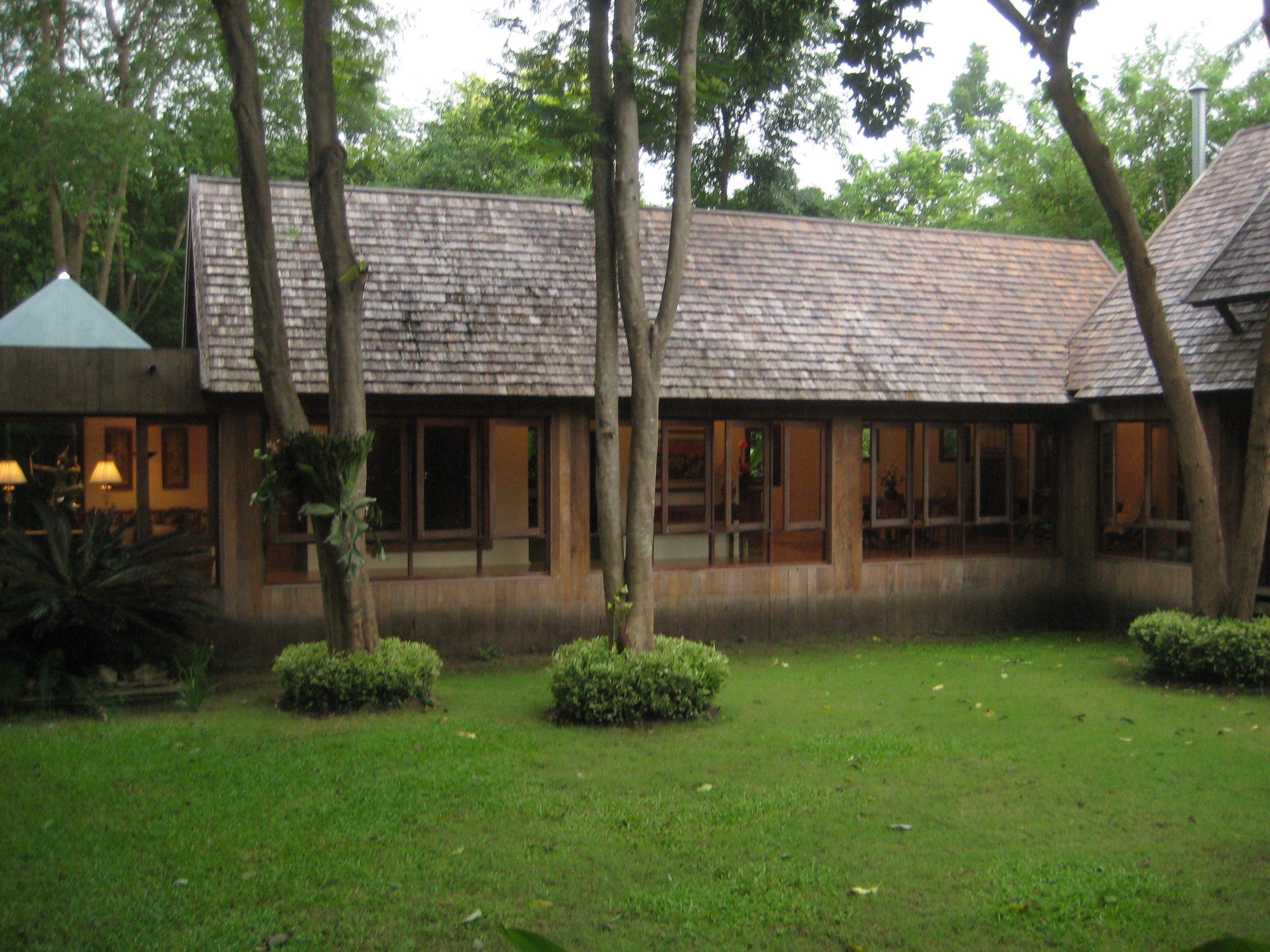 A building with a tiled roof, surrounded by trees and a grassy area.