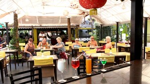 An outdoor restaurant with yellow tablecloths, multiple dining tables, and chairs. - Alor Grande Holiday Resort (Candolim)