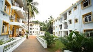 A corridor with buildings on either side, featuring balconies and a pathway. - Alor Grande Holiday Resort (Candolim)