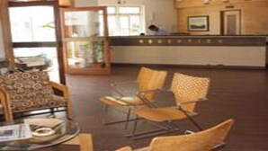 A reception area with a counter, chairs, and a glass display case. - Alor Grande Holiday Resort (Candolim)