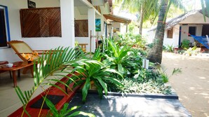 A covered outdoor area with a wooden bench, a hammock, and various plants.