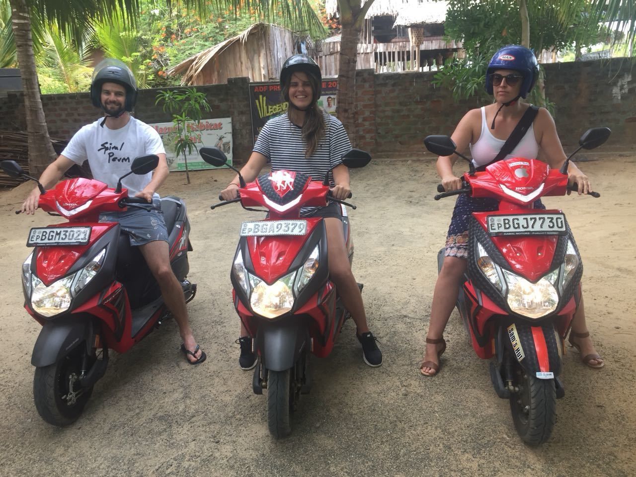 Tres personas montadas en scooters rojos con placas de matrícula visibles.