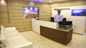 Un área de recepción con mostrador, un reloj, un acuario de pared y un cartel de una mezquita.