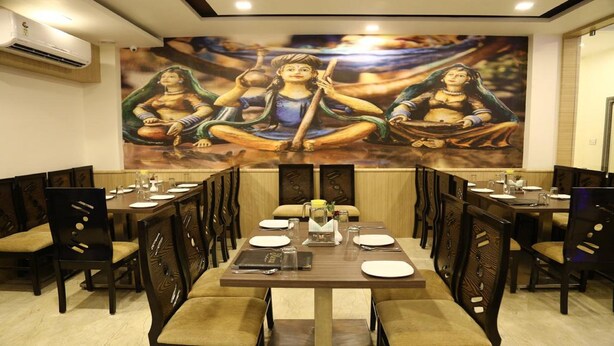 Comedor con un mural de deidades, sillas de madera y mesas dispuestas para comer.