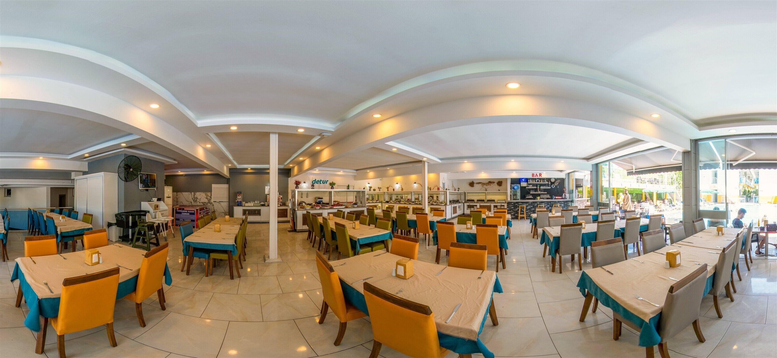 A spacious restaurant with multiple dining areas, a bar, and a kitchen visible in the background.