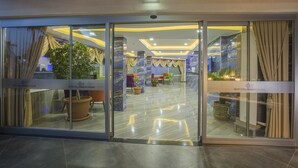 A hotel lobby with glass doors, potted plants, and seating areas. - Arsi Enfi City Beach Hotel (Alanya)