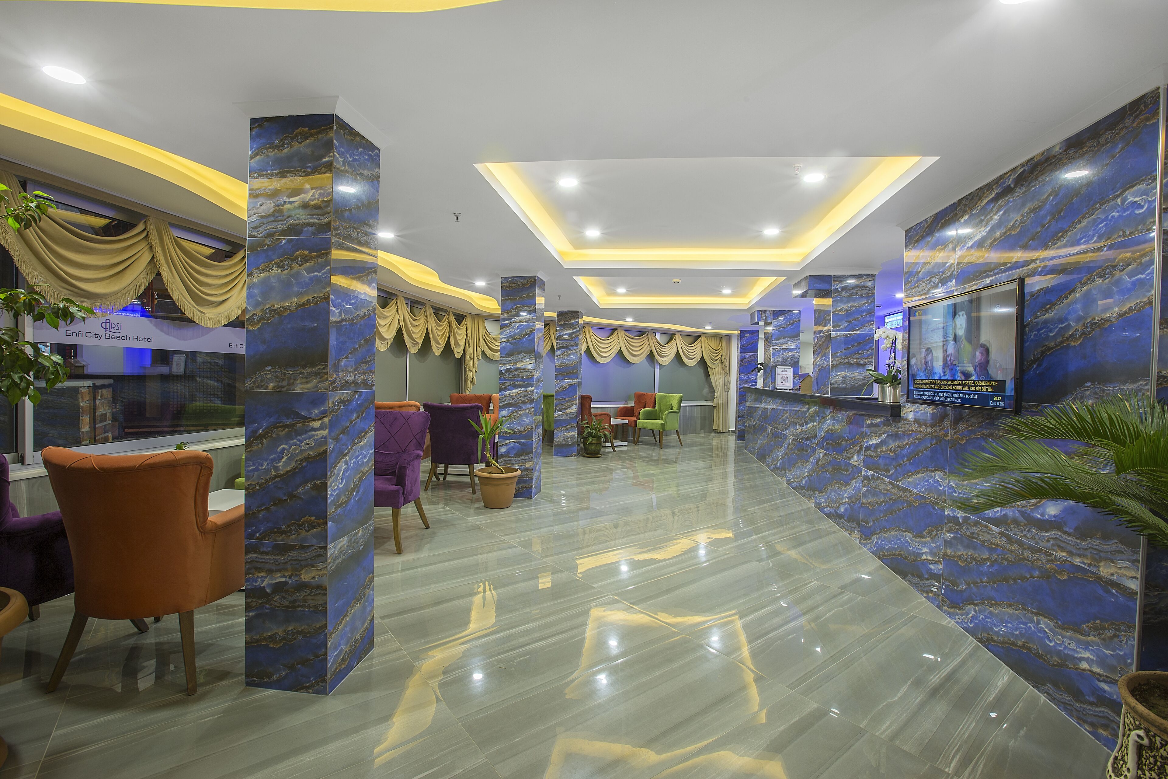 A hotel lobby with marble walls, a reception desk, and seating areas.