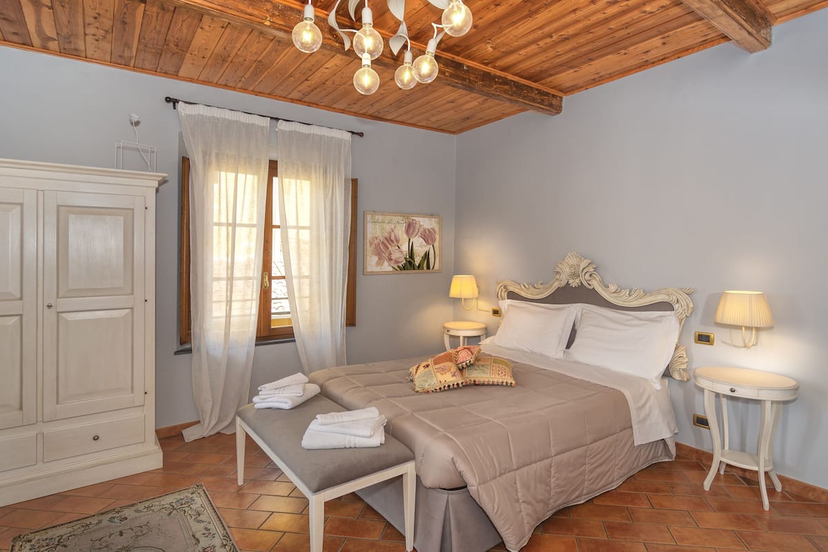A bedroom with a bed, bedside tables, a wardrobe, and a window with curtains.