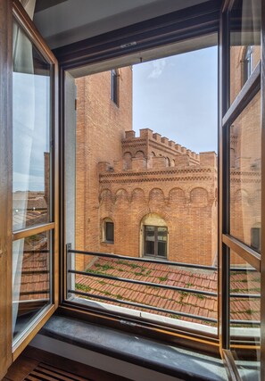 A view from a window of a brick building with arched windows and a balcony. - Rinascimento Bed & Breakfast (Pisa)