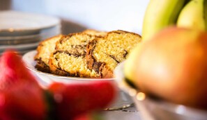 A plate of bread with a golden-brown crust, possibly a type of brioche or sweet bread, with a visible swirl pattern.