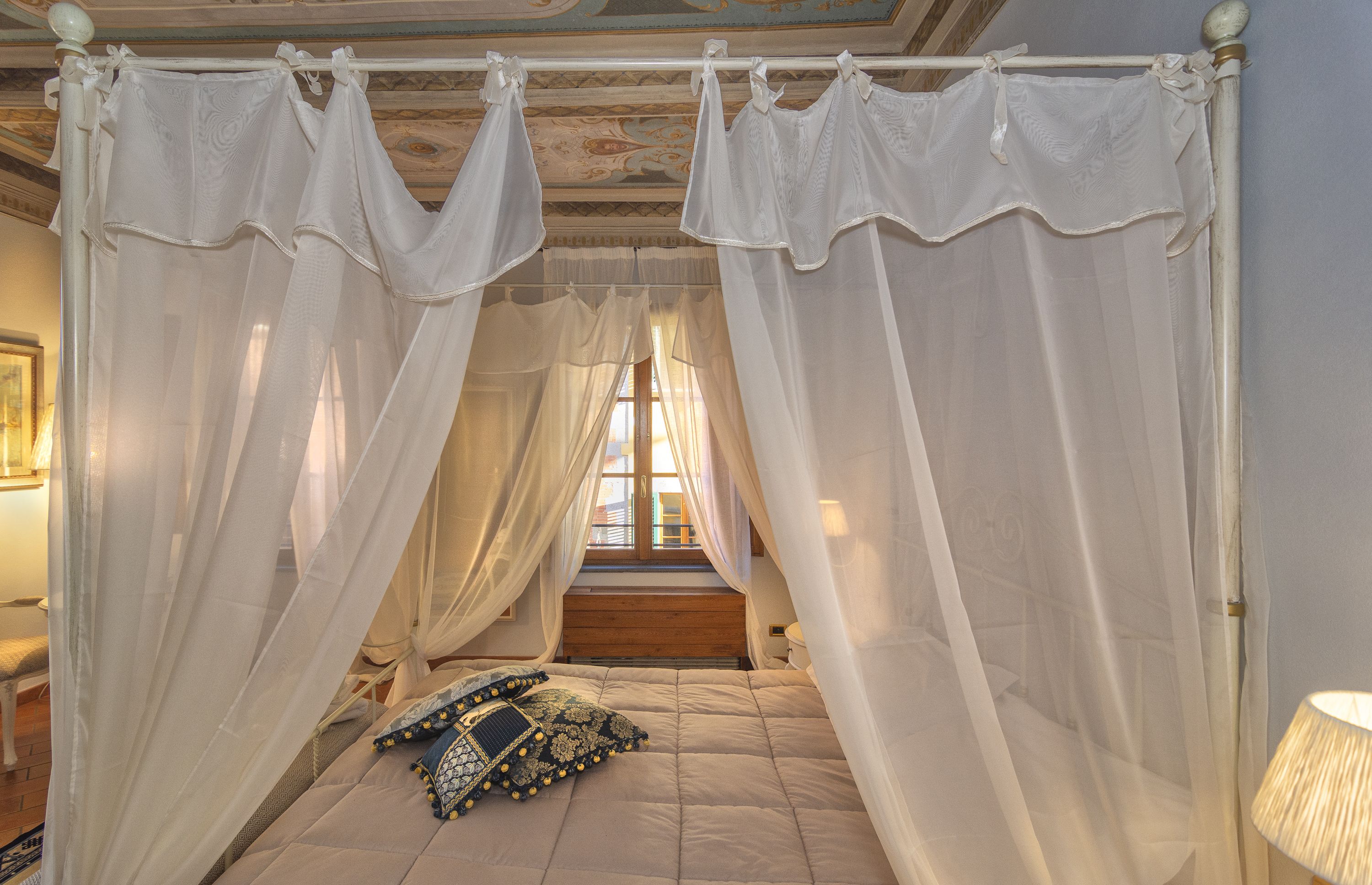 A four-poster canopy bed with a view of the outside through a window.