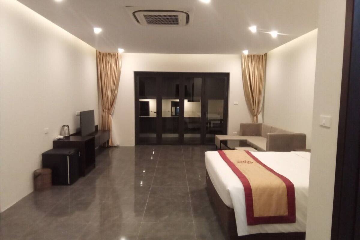 A modern hotel room with a large bed, a flat-screen TV, a desk, and a seating area.
