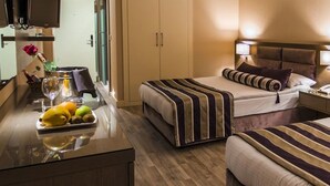 A hotel room with two beds, a bedside table with a lamp, a mirror, and a fruit bowl. - Treebo Ashoka Palace Ujjain (Ujjain)