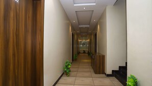A hallway with wooden doors, tiled flooring, and potted plants. - Treebo Ashoka Palace Ujjain (Ujjain)