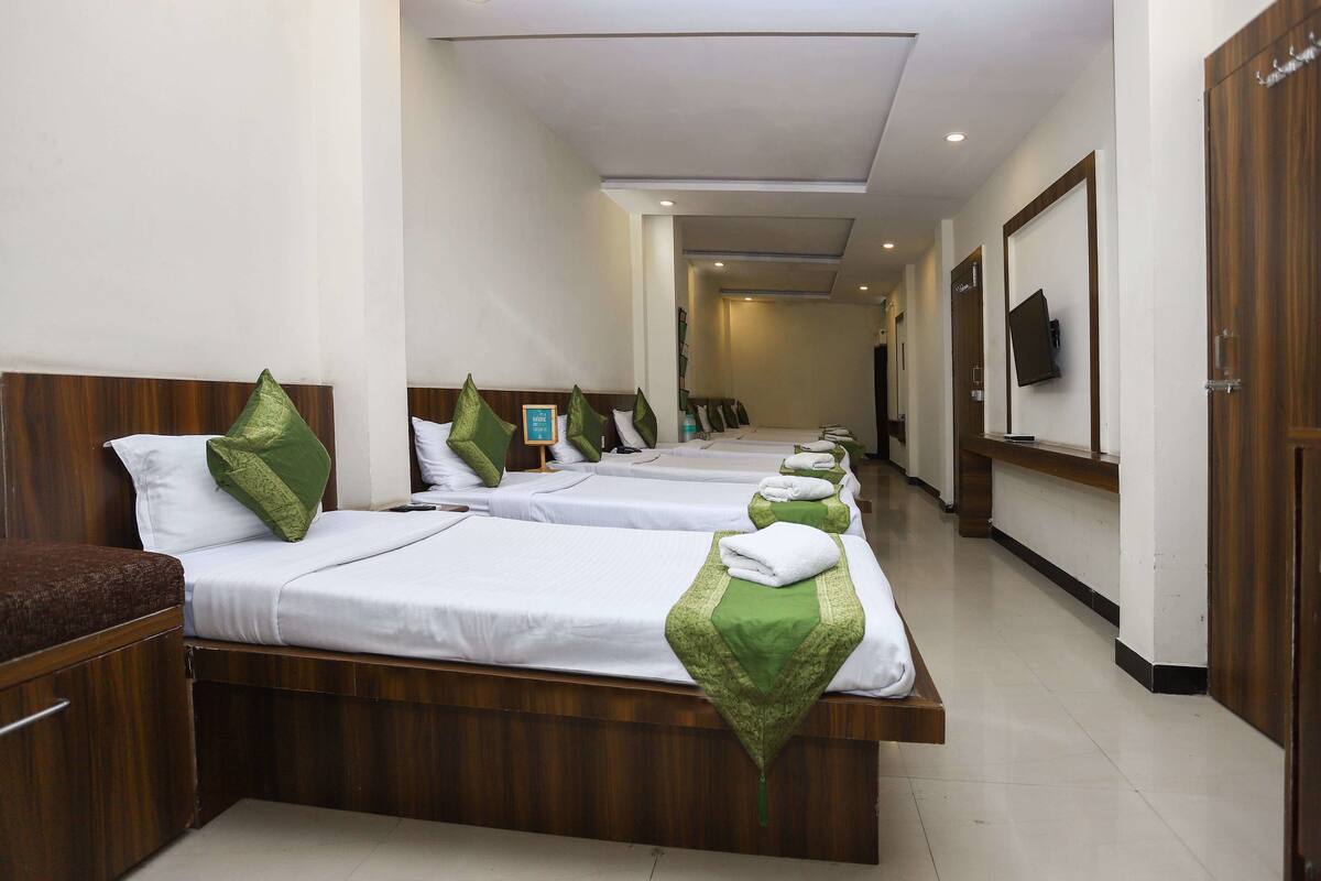 Habitación de hotel con varias camas, cabeceros de madera y almohadas verdes.