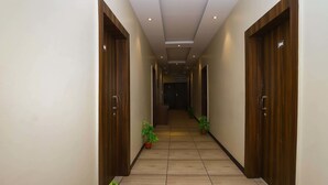 A hallway with wooden doors, potted plants, and a tiled floor. - Treebo Ashoka Palace Ujjain (Ujjain)