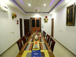 A dining area with a long table set for a meal, chairs around the table, a ceiling fan, and a framed picture on the wall.