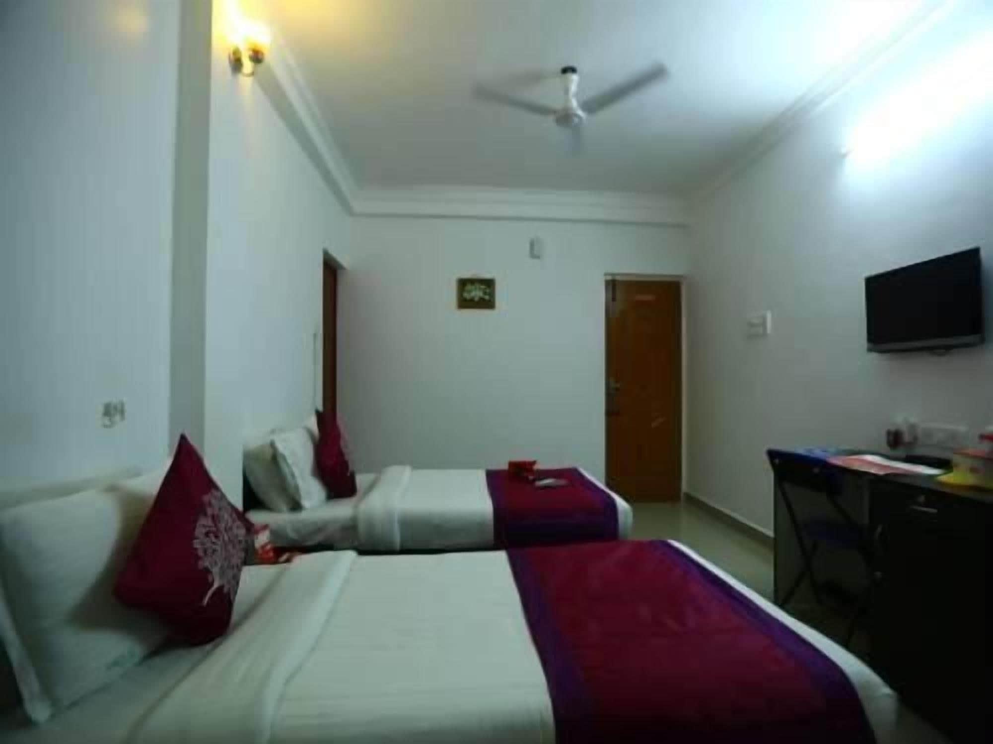 A hotel room with two beds, a ceiling fan, a TV, and a desk.