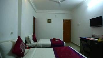 A hotel room with two beds, a ceiling fan, a TV, and a desk.