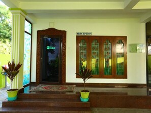 A reception area with a wooden door, a reception sign, and potted plants.