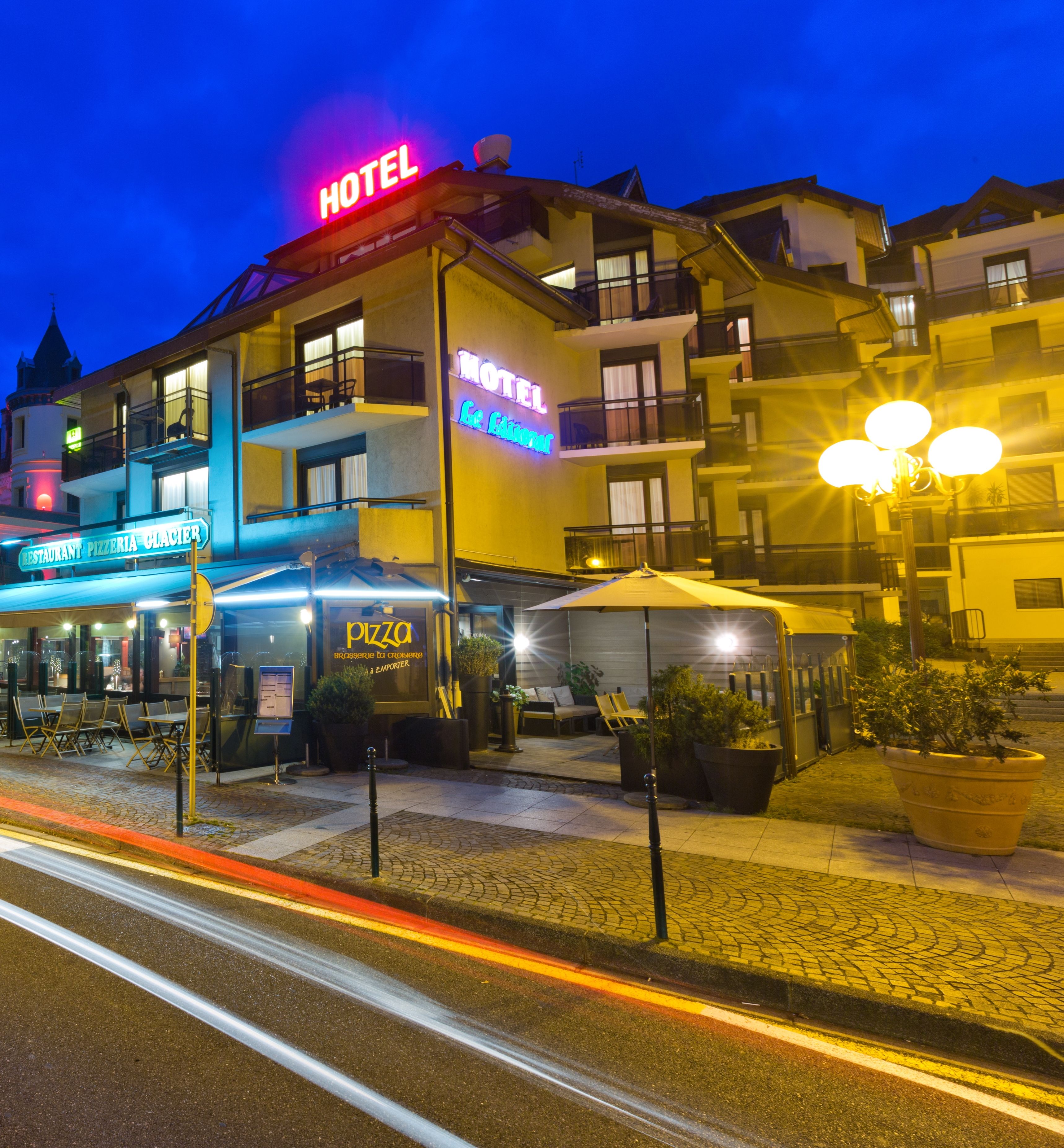 Ein Hotel mit einer Neonreklame, einem Restaurant und Außenplätzen.