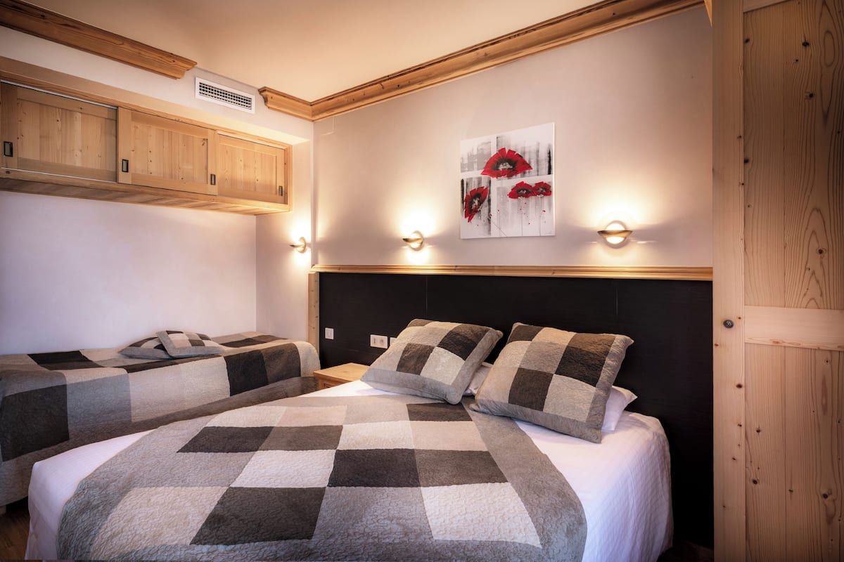 A bedroom with two beds, wooden headboards, and a wall-mounted artwork.