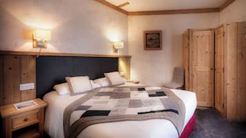 A bedroom with a large bed, wooden headboard, two bedside tables, a nightstand, a wall-mounted lamp, a framed picture, and a wardrobe.