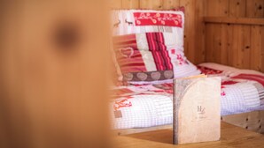 A wooden bed with a quilt, a wooden nightstand with a book, and a wooden wall. - Logis Hôtel le Littoral (Evian-les-Bains)